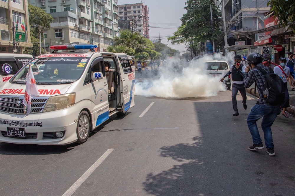 Protesters and journalists run as police fire tear gas while charging toward them during a demonstration against the military coup, Yangon, Myanmar, 27 February 2021, Santosh Krl/SOPA Images/LightRocket via Getty Images