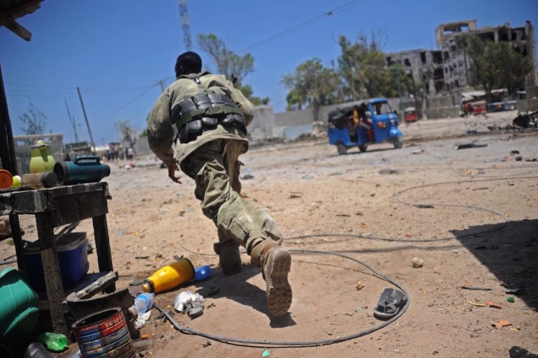 A Somali soldier runs for cover at the scene of two explosions set off near the ministries of public works and labour in Mogadishu, 23 March 2019, in an attack claimed by Al-Shabaab, MOHAMED ABDIWAHAB/AFP via Getty Images