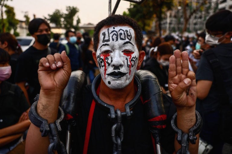 A pro-democracy protester wearing chains around his neck makes the three-finger salute outside the Criminal Court, Bangkok, Thailand, 9 March 2021, JACK TAYLOR/AFP via Getty Images