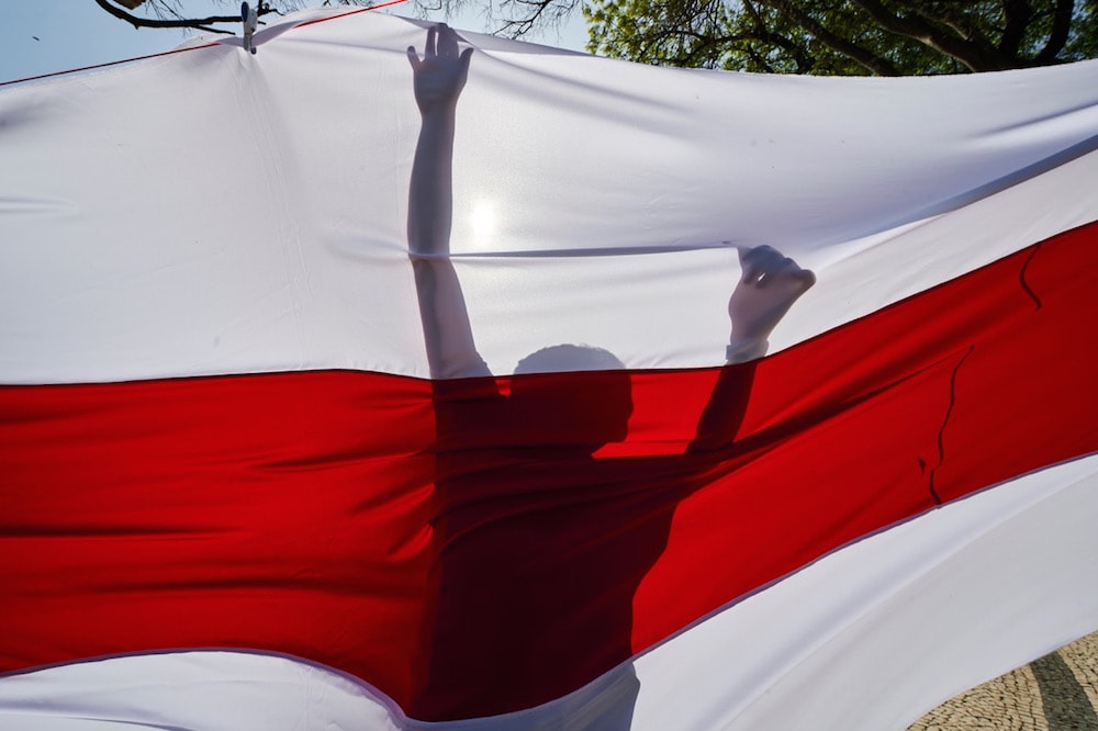 A demonstrator is silhouetted while hanging a Belarusian flag during a protest attended by opposition leader Svetlana Tikhanovskaya, in Lisbon, Portugal, 6 March 2021, Horacio Villalobos/Corbis/Corbis via Getty Images