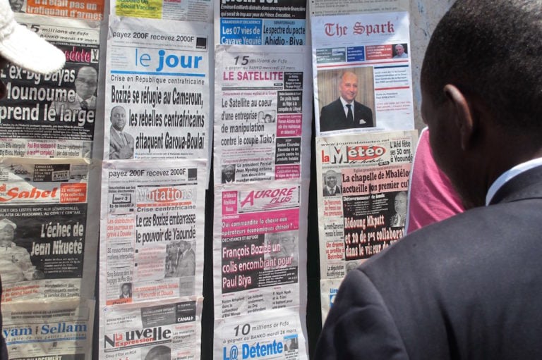 Un homme lit des gros titres des journaux, à un kiosque, Yaoundé, Cameroun, le 26 mars 2013, Reinnier KAZE/AFP via Getty Images