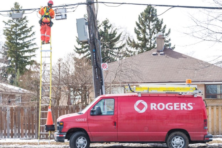 A company technician for Rogers, one of Canada's Big Telecom providers, working on a ladder, in Toronto, Ontario, 13 March 2015, Roberto Machado Noa/LightRocket via Getty Images
