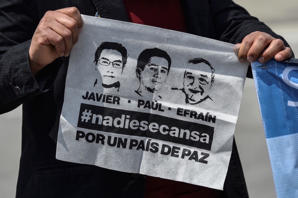 Un hombre lleva un pañuelo con los imagenes de los periodistas Javier Ortega, Paúl Rivas y Efraín Segarra, en Palmira, Colombia, el 22 de junio de 2018, LUIS ROBAYO/AFP via Getty Images