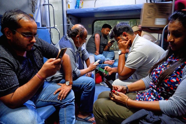 Passengers on a railway coach browse their mobile phones, near Delhi, India, 21 March 2021, Avishek Das/SOPA Images/LightRocket via Getty Images