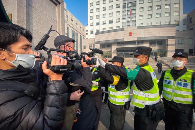 Shanghái, China, el 28 de diciembre de 2020. Unos policías bloquean a unos periodistas que tratan de filmar afuera de un tribunal, durante el juicio de un ciudadano que trató de informar sobre el Covid-19 en Wuhan, LEO RAMIREZ/AFP via Getty Images