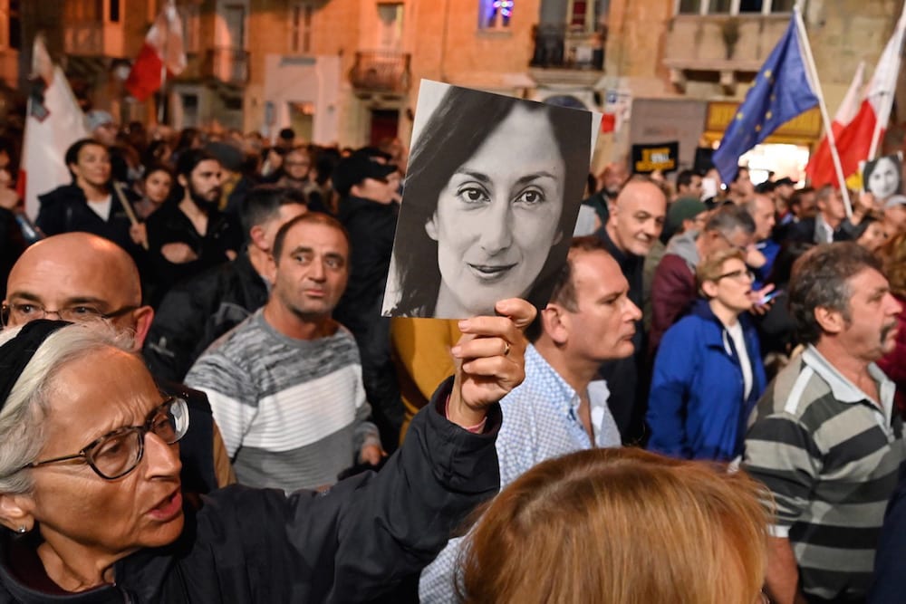 People hold placards and photos of killed journalist Daphne Caruana Galizia during a protest outside the police headquarters, in Valletta, Malta, 3 December 2019, ANDREAS SOLARO/AFP via Getty Images