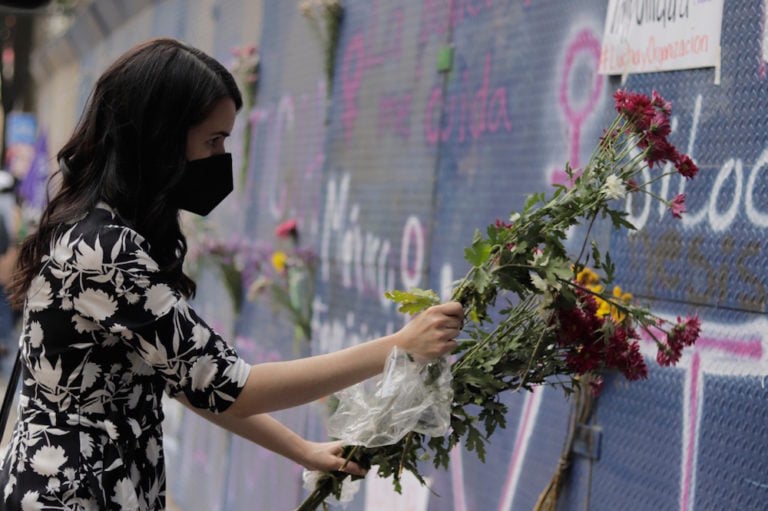 Una mujer deja flores en un sitio llenado con carteles y grafiti denunciando la violencia contra las mujeres, en la Ciudad de México, México, el 29 de marzo de 2021, Gerardo Vieyra/NurPhoto