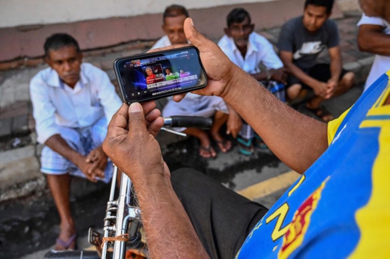 A man watches election results on a mobile phone in Colombo, Sri Lanka, 17 November 2019, ISHARA S. KODIKARA/AFP via Getty Images
