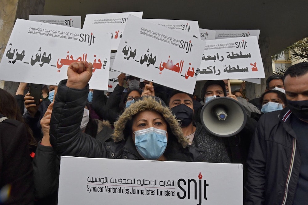 Journalists hold up signs reading in Arabic "fourth estate, not kneeling estate" and "journalists' rights are not privileges", as they demonstrate outside the headquarters of the Tunis Africa Press (TAP) news agency, in Tunis, 15 April 2021, FETHI BELAID/AFP via Getty Images