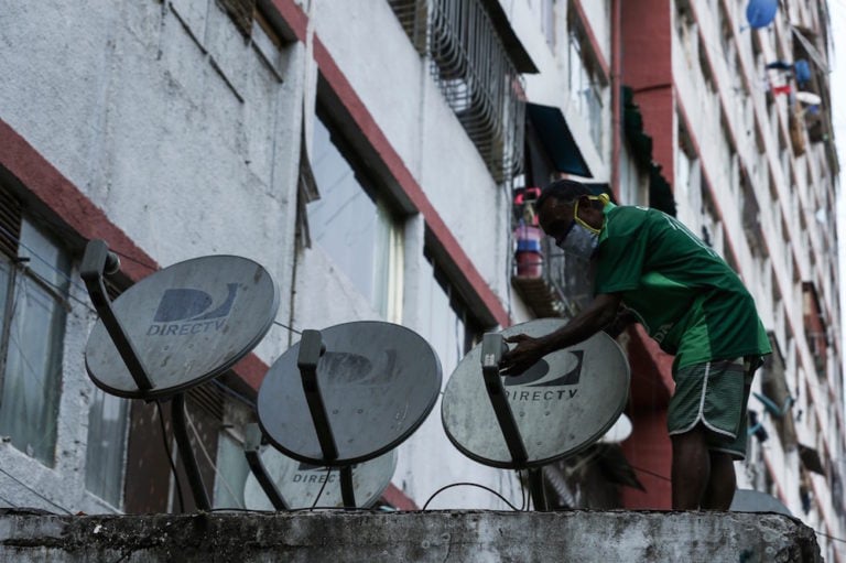 Un hombre con una máscara revisa una antena de television satélite, en Caracas, Venezuela, el 19 de mayo de 2020, Pedro Rances Mattey/picture alliance via Getty Images