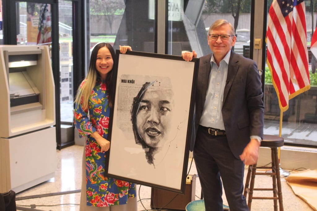 Mai Khoi recibe una copia de su ilustración del fundador de IFEP, Greg Victor. Foto de Matt Petras