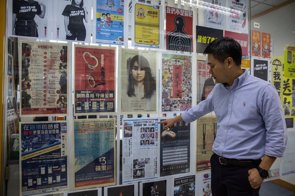 The "Apple Daily" editor-in-chief points to a copy of the first front page, in the newsroom in Hong Kong, 13 May 2021; a shadow of fear hangs over the paper as its owner has been jailed and reporters are asking themselves "Are we next?" ISAAC LAWRENCE/AFP via Getty Images