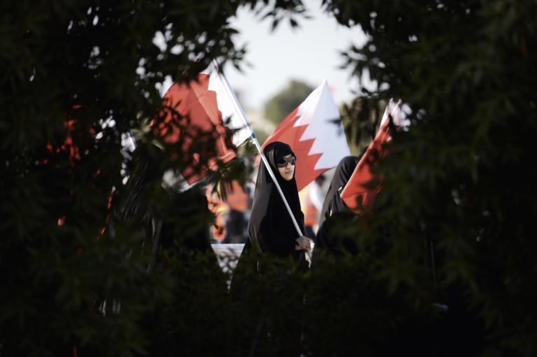 امرأة بحرينية تحمل العلم الوطني خلال مظاهرة مناهضة للحكومة في قرية جنوسان، غرب المنامة، بتاريخ 19 أيلول 2014. (الصورة من: محمد الشيخ / الوكالة الفرنسية عبر Getty Images).