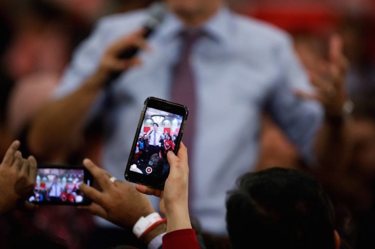 Seen through people's phones, Prime Minister Justin Trudeau speaks at a campaign rally ahead of the federal election, Vaughan, Canada, 18 October 2019, Cole Burston/Getty Images