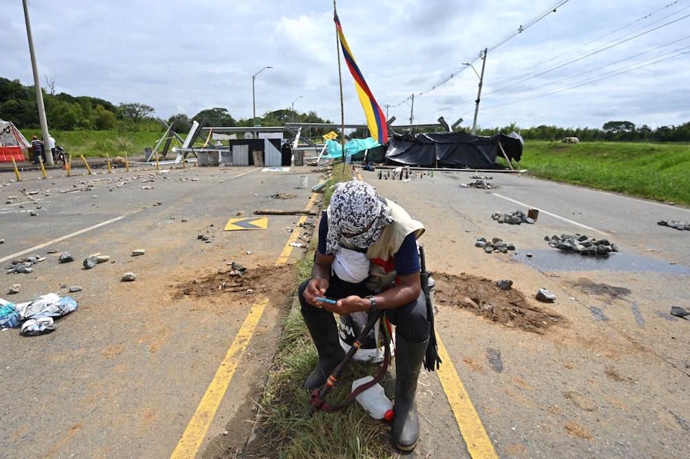 Un manifestante indígena revisa su celular cerca de una barricada, durante el Paro Nacional, Cali, Colombia, el 10 de mayo de 2021, LUIS ROBAYO/AFP via Getty Images