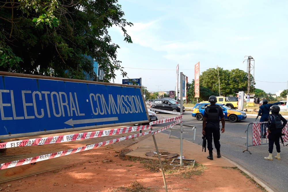 Police officers stand near a signpost indicating the way to the Electoral Commission, in Accra, Ghana, 8 December 2020, as Ghanaians await results of presidential and parliamentary elections, PIUS UTOMI EKPEI/AFP via Getty Images