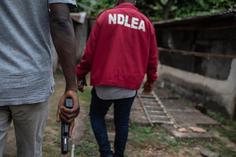 National Drug Law Enforcement Agency (NDLEA) officials walk toward the site of a clandestine methamphetamine lab busted by the NDLEA, at Obinugwu village, Nigeria, 22 November 2018, STEFAN HEUNIS/AFP via Getty Images