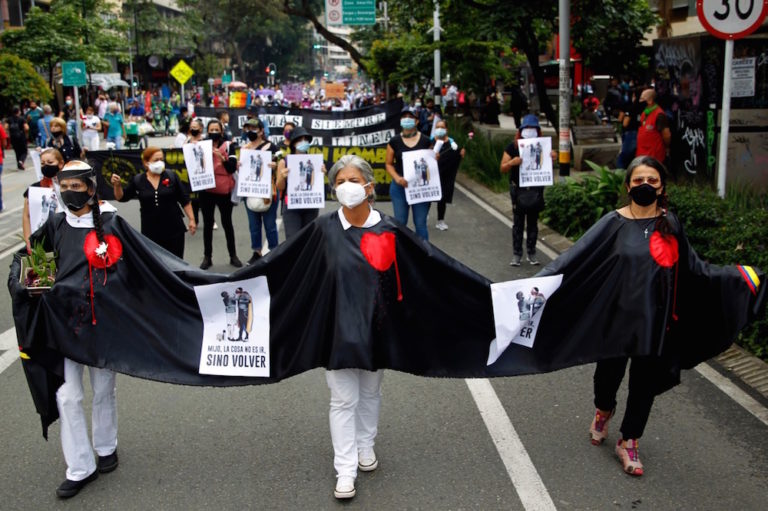 Demonstrators wear a black cape with red hearts painted to honour the victims on the front line of the national strike, during a protest organized by relatives of victims of enforced disappearance, in Medellín, Colombia, 27 May 2021, Fredy Builes/Getty Images