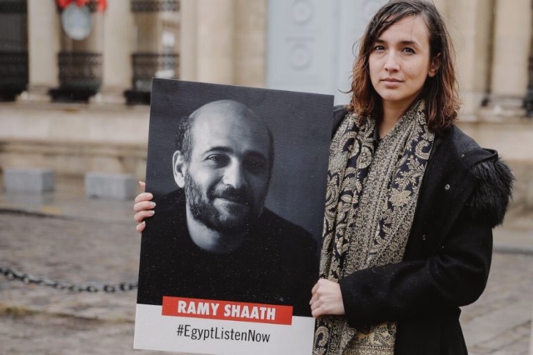 Céline Lebrun Shaath,   prominent human rights defender and wife of arbitrary imprisoned Palestinian-Egyptian human rights defender Ramy Shaath, with a poster calling for his release. Free Ramy Shaath, https://www.freeramyshaath.com/