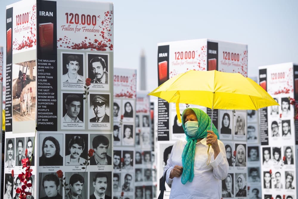 A woman walks past some of the thousands of photos of people killed in Iran during the 1988 massacre as well as during more recent anti-regime uprisings, at a photo exhibit near the US Capitol in Washington, DC, U.S., 4 September 2020, SAUL LOEB/AFP via Getty Images
