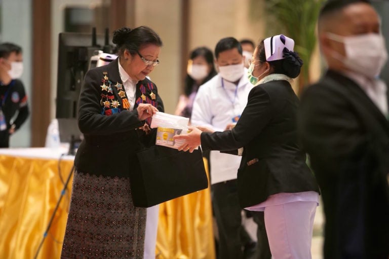 A delegate takes a face mask for protection from COVID-19, at the entrance of the venue for the 11th Congress of the Lao People's Revolutionary Party, in Vientiane, 13 January 2021, Xinhua/Kaikeo Saiyasane via Getty Images