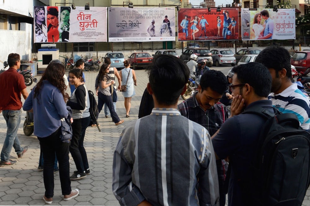 Pedestrians walk past cinema posters in Kathmandu, Nepal, 6 June 2016, PRAKASH MATHEMA/AFP via Getty Images