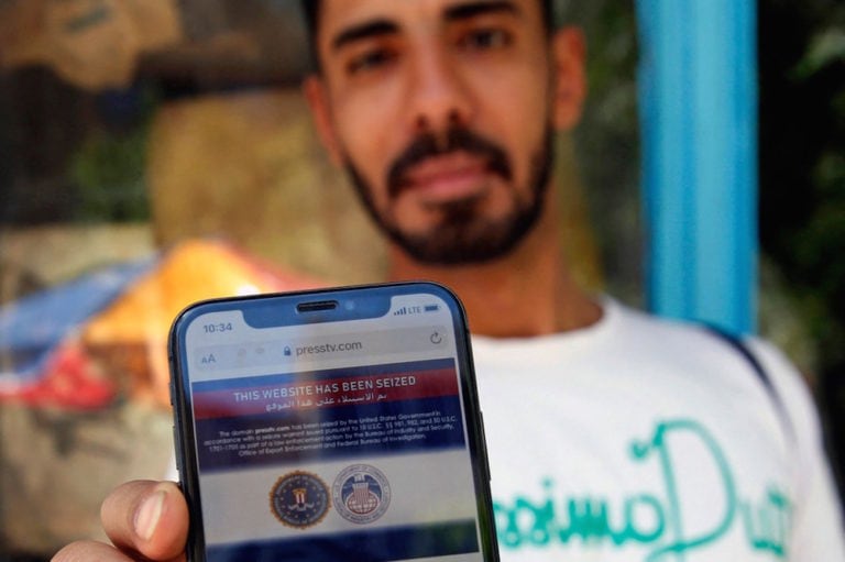 An Iranian man shows on his mobile phone a statement declaring the website of Iran's English-language television station Press TV "has been seized by the United Government", in Tehran, 23 June 2021, -/AFP via Getty Images