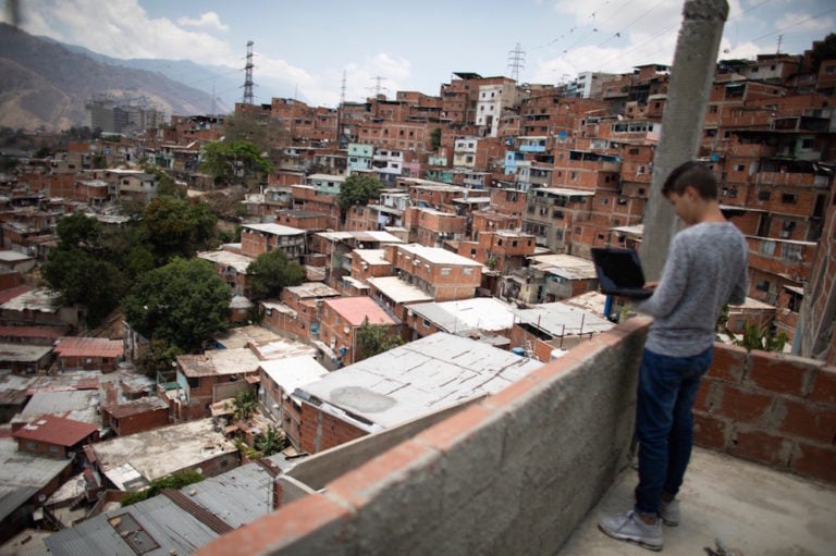 Un estudiante trata a conectar a internet, en el techo de su casa, en Caracas, Venezuela, el 27 de abril de 2020, Leonardo Fernandez Viloria/Getty Images