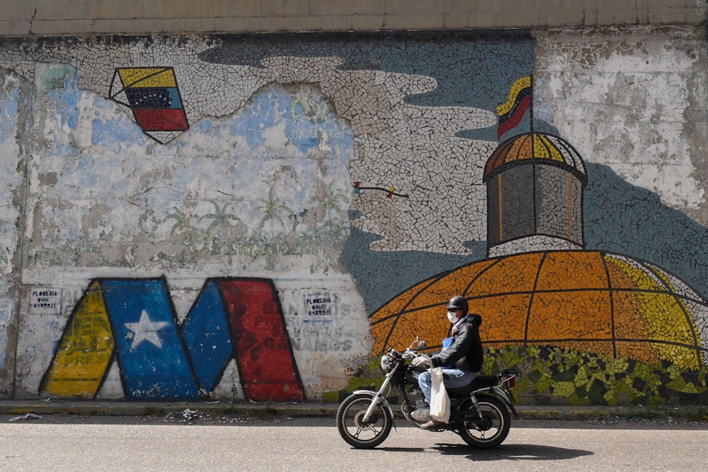 Un hombre anda en motocicleta, en frente de un mural con una representación de la Asamblea Nacional, en Caracas, Venezuela, el 1 de diciembre de 2020, FEDERICO PARRA/AFP via Getty Images
