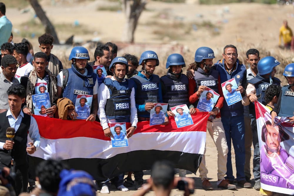 Taiz, Yemen, 2 January 2021. Journalists and mourners hold placards and banners during the funeral of TV reporter Adeeb al-Janani who was killed in an attack on the airport in Aden, AHMAD AL-BASHA/AFP via Getty Images