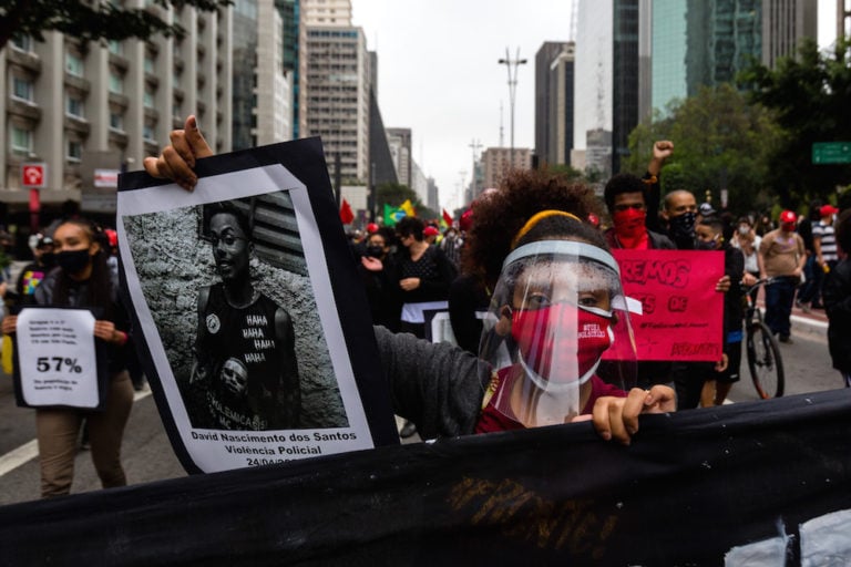 A demonstrator holds a sign against police violence in Brazil, during a protest in Sao Paulo, 14 June 2020, Diego Baravelli/picture alliance via Getty Images