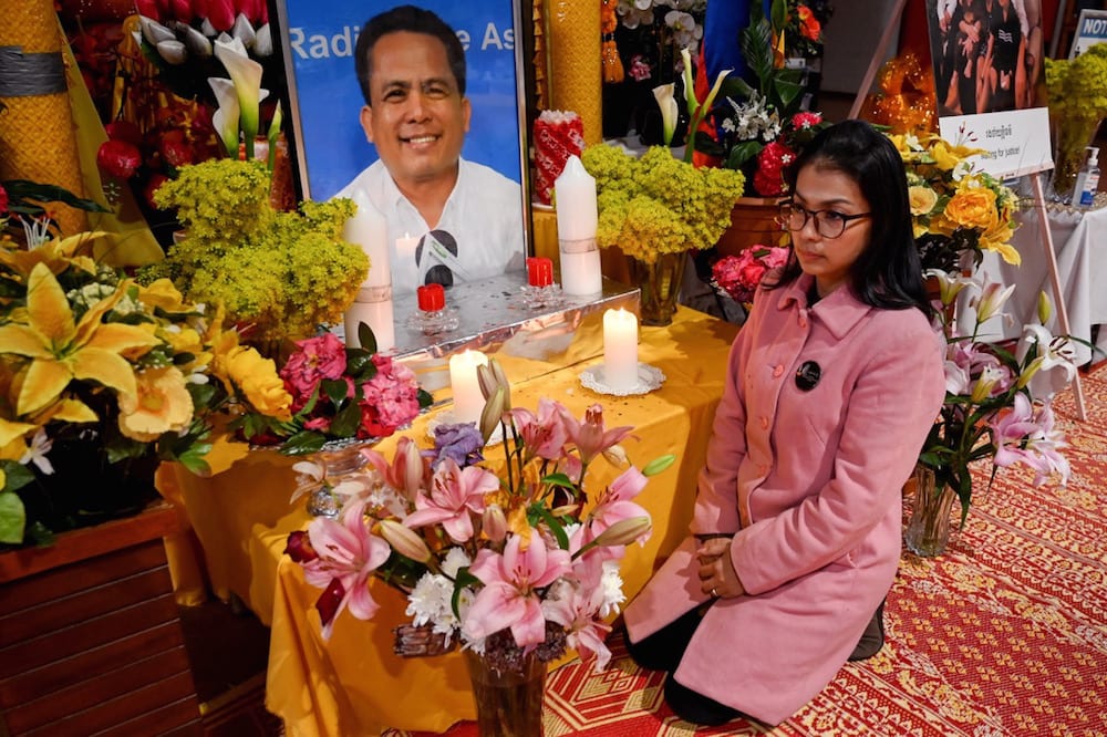 Bou Rachna, widow of the slain Cambodian political commentator Kem Ley, kneels in front of a photo of Ley, at a Buddhist temple in Melbourne, australia, 9 July 2021, WILLIAM WEST/AFP via Getty Images