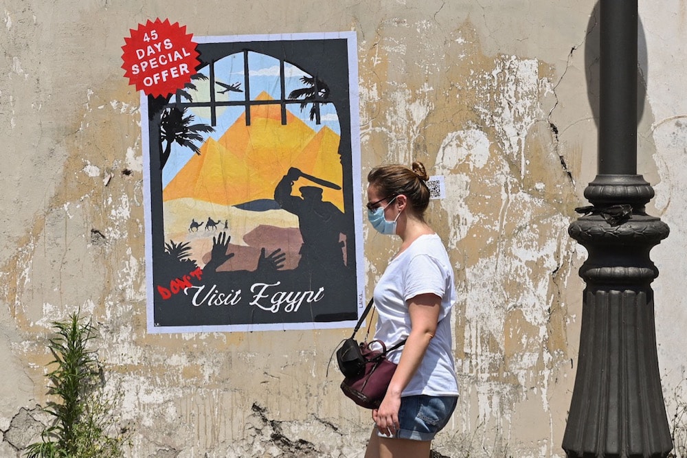 A woman walks past a poster by Italian street artist Laika, entitled "Don't visit Egypt", placed on a wall near the Egyptian embassy in Rome, on 16 June 2021, after the extension of the detention in Egypt of another researcher, Patrick Zaki. ALBERTO PIZZOLI/AFP via Getty Images