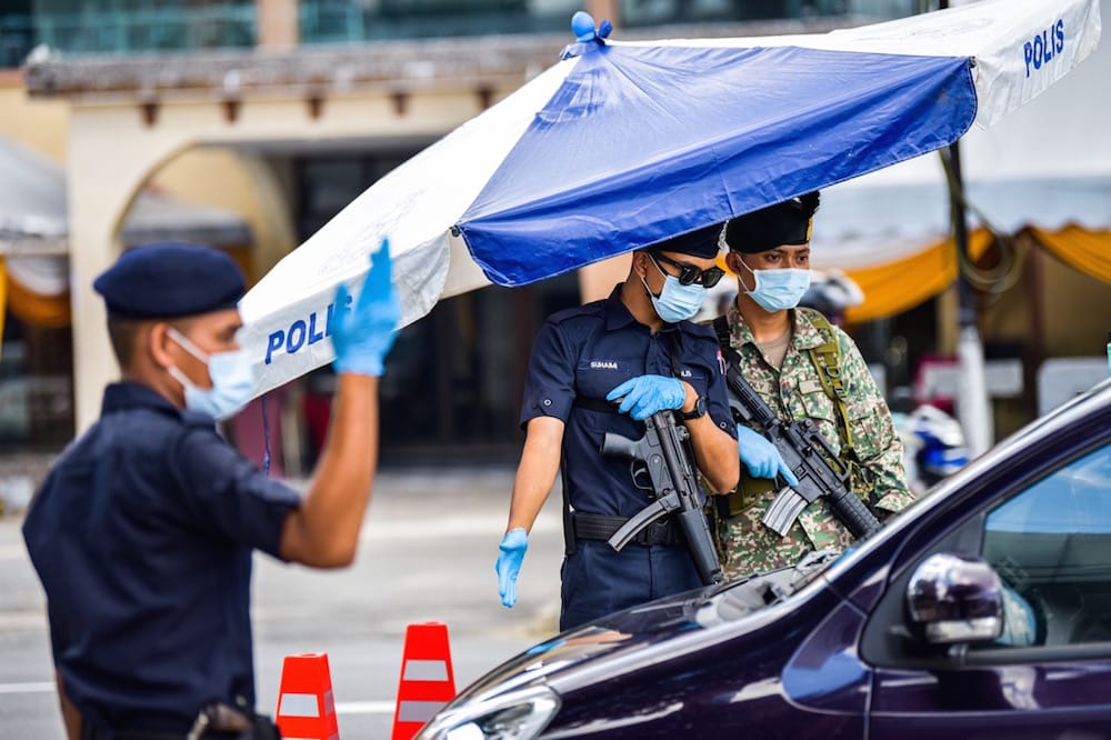 Police officers and a soldier check vehicles at a roadblock in Kuala Lumpur, Malaysia, 1 June 2021, Zhu Wei/Xinhua via Getty Images