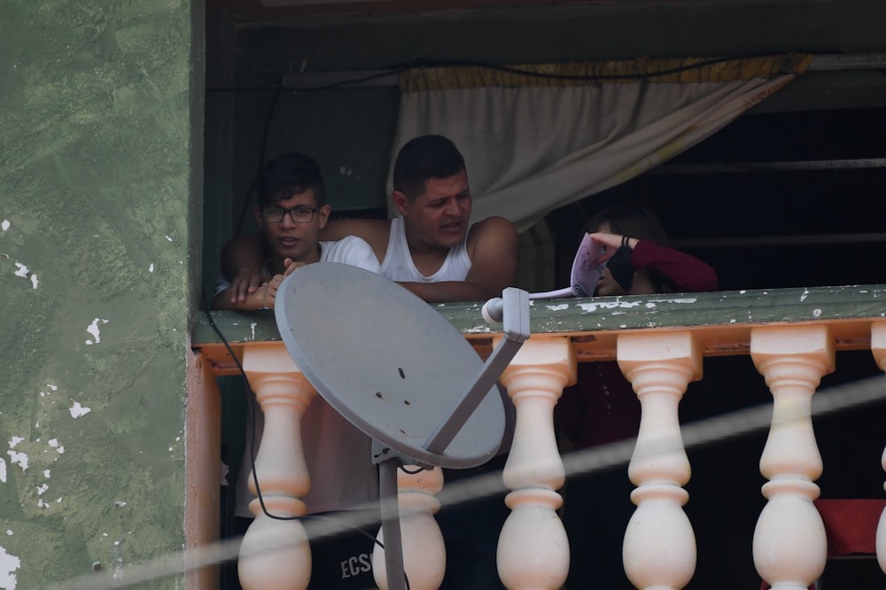 Una familia en su balcón al lado de una antena parabólica, en el barrio Petare, Caracas, Venezuela, el 19 de mayo de 2020, FEDERICO PARRA/AFP via Getty Images