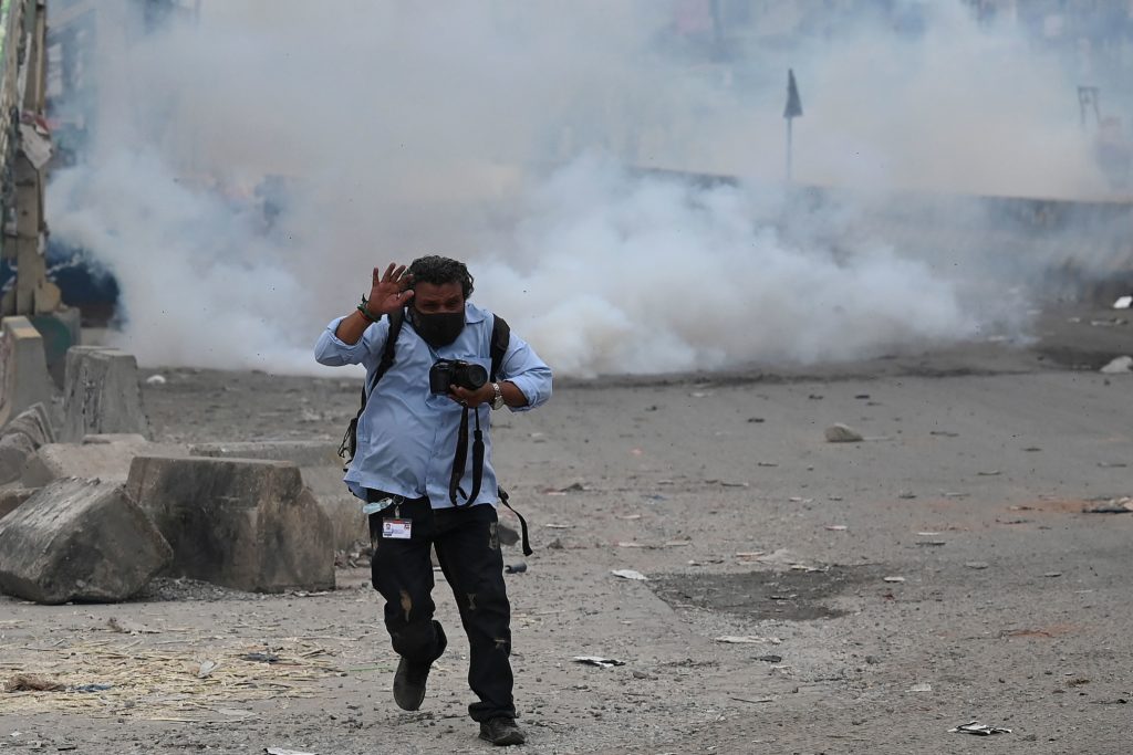 A photojournalist reacts while riot policemen clash with supporters of the Tehreek-e-Labbaik Pakistan (TLP) party during a protest, in Islamabad, Pakistan, 13 April 2021, AAMIR QURESHI/AFP via Getty Images