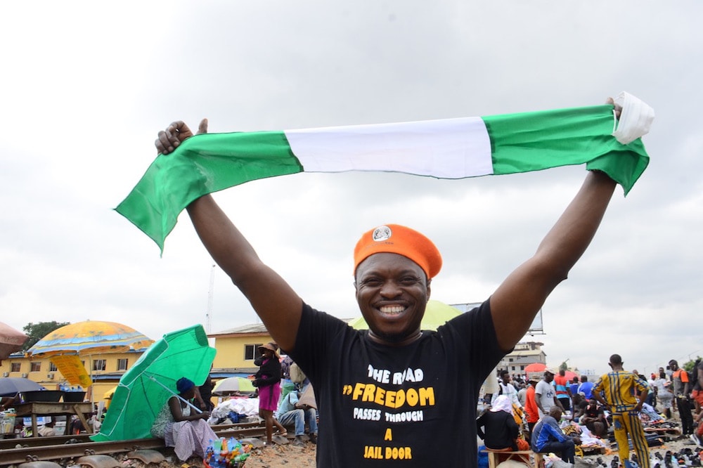 Journalist and activist Agba Jalingo raises a Nigerian flag during a protest against government practices and in support of activist Omoyele Sowore, in Lagos, 5 August 2020, Olukayode Jaiyeola/NurPhoto via Getty Images