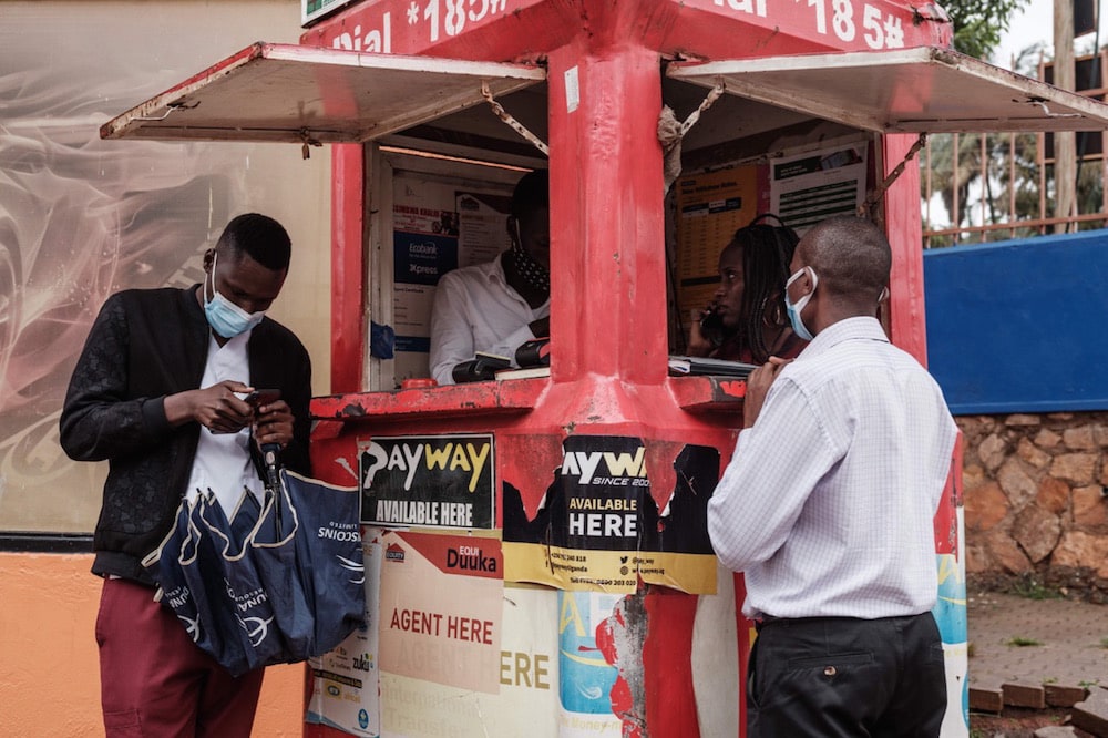 People wait at a mobile phone agent's kiosk in Kampala, Uganda, 18 January 2021, following the partial restoring of the internet after an almost complete blackout. YASUYOSHI CHIBA/AFP via Getty Images