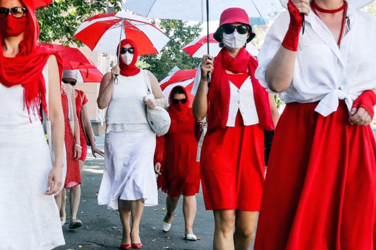 Belarusian women march holding umbrellas in the colours of the former white-red-white flag of Belarus in solidarity with those who are imprisoned, in Minsk, 18 July 2021, STRINGER/AFP via Getty Images