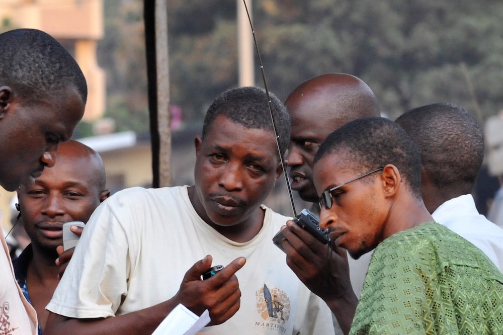 Men gather to listen to the news on the radio, in Kindia, Guinea, 16 December 2009, SIA KAMBOU/AFP via Getty Images