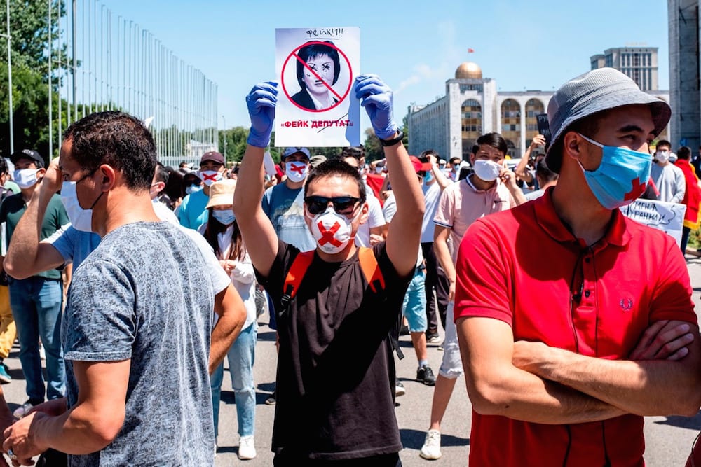 A man holds up a portrait of an MP who had proposed a draft law that would impact on press and internet freedom, during a protest against the bill, in Bishkek, Kyrgyzstan, 29 June 2020, DANIL USMANOV/AFP via Getty Images