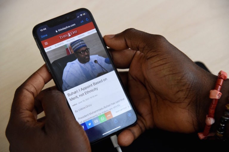 A journalist, looking for information on his smartphone, reads an article on President Buhari during the suspension of Twitter, in Lagos, Nigeria, 10 June 2021, PIUS UTOMI EKPEI/AFP via Getty Images