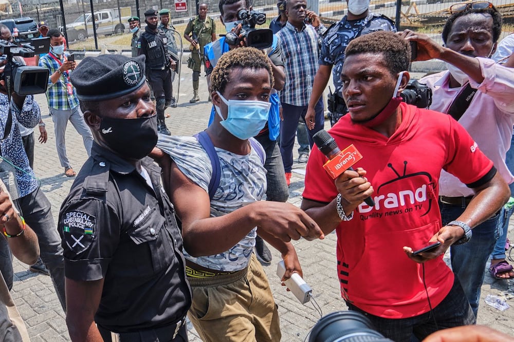 Reporters are on the scene as a police officer arrests a protestor during a demonstration against the re-opening of the Lekki toll plaza in Lagos, Nigeria, 13 February 2021, Adeyinka Yusuf/Majority World/Universal Images Group via Getty Images