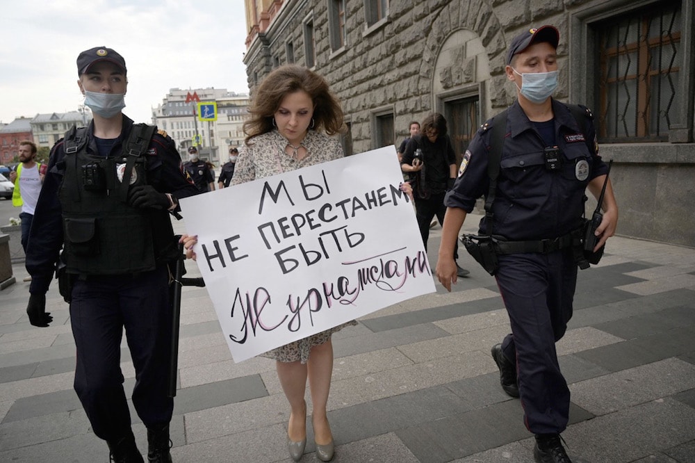 Police officers detain a journalist who holds a placard that says "We don't stop being journalists", in solidarity with colleagues who were labelled "foreign agents", near the headquarters of Russia's Federal Security Service (FSB), in Moscow, 21 August 2021, NATALIA KOLESNIKOVA/AFP via Getty Images