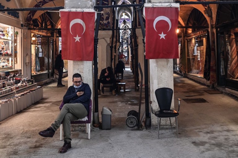 A shop owner looks at his phone as he waits for customers inside the Grand Bazaar, Istanbul, Turkey, 22 March 2021, OZAN KOSE/AFP via Getty Images