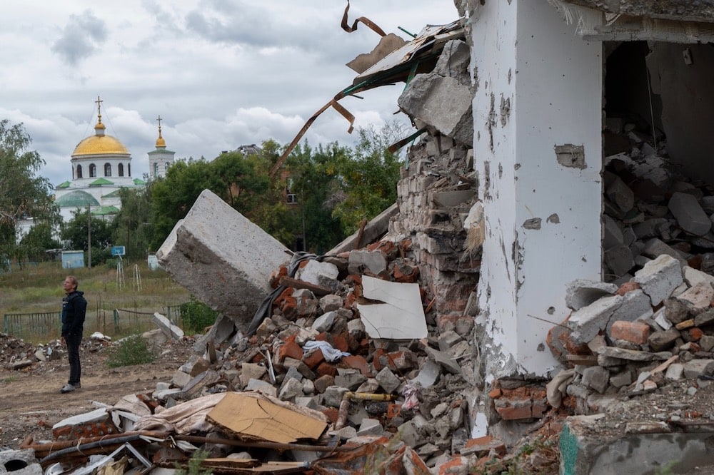 A reporter stands near ruins of residential buildings destroyed as a result of shelling, in Izium, Ukraine, 14 September 2022. Viacheslav Mavrychev/Suspilne Ukraine/JSC "UA:PBC"/Global Images Ukraine via Getty Images