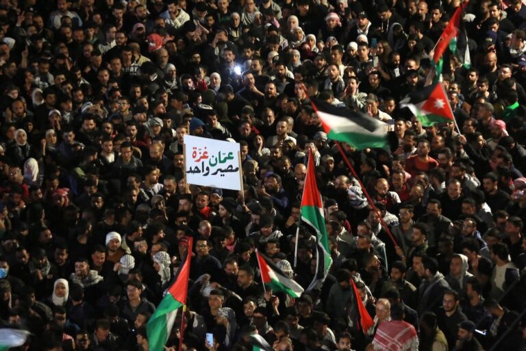أشخاص يحملون لافتات وأعلام خلال مظاهرة ضد الحرب على غزة بالقرب من السفارة الإسرائيلية في العاصمة الأردنية عمان، بتاريخ ٢٨ مارس / آذار للعام ٢٠٢٤، تصوير خليل المزرعاوي من فرانس برس